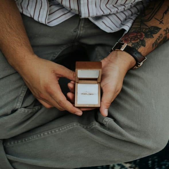 man sitting thoughtfully while holding a ring box