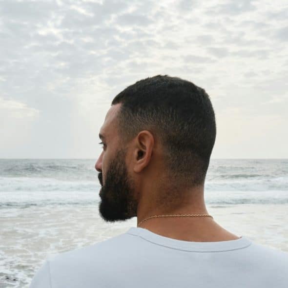 A man standing on the beach looking at the ocean.