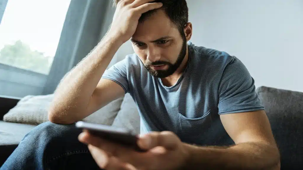 man looking at his phone, thinking about reaching out