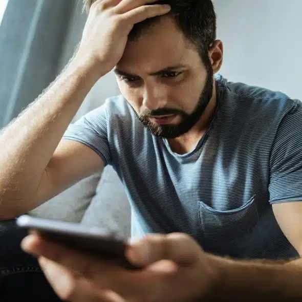 man looking at his phone, thinking about reaching out