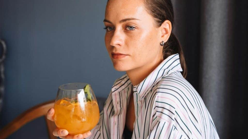 A woman holding an orange drink