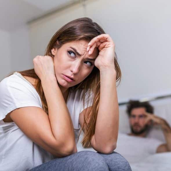 A worried woman sitting on a bed