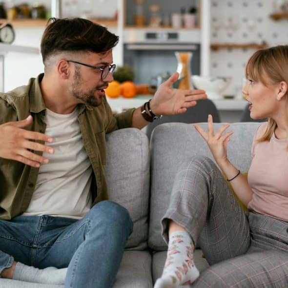 A man and a woman arguing while sitting on a couch.