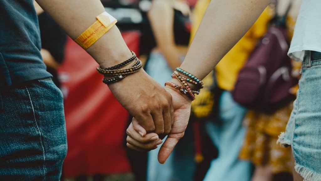 A man and a woman holding hands in a crowd.