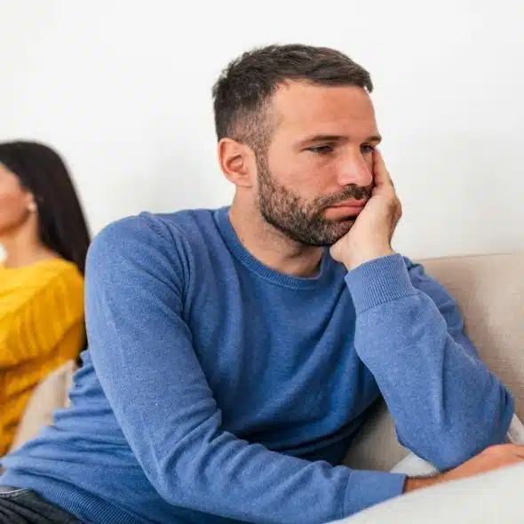 man sitting with partner but looking slightly conflicted