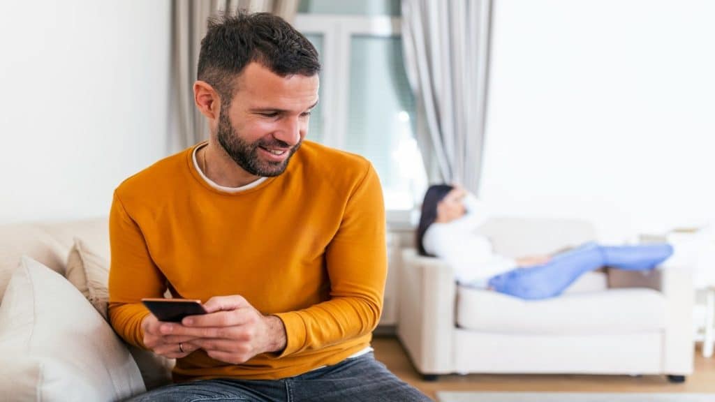 man sitting next to partner while distracted