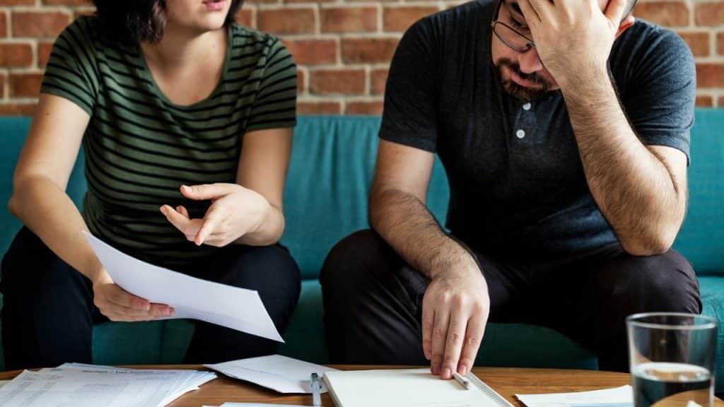 A woman gestures toward a paper while a man rests his head in his hand.