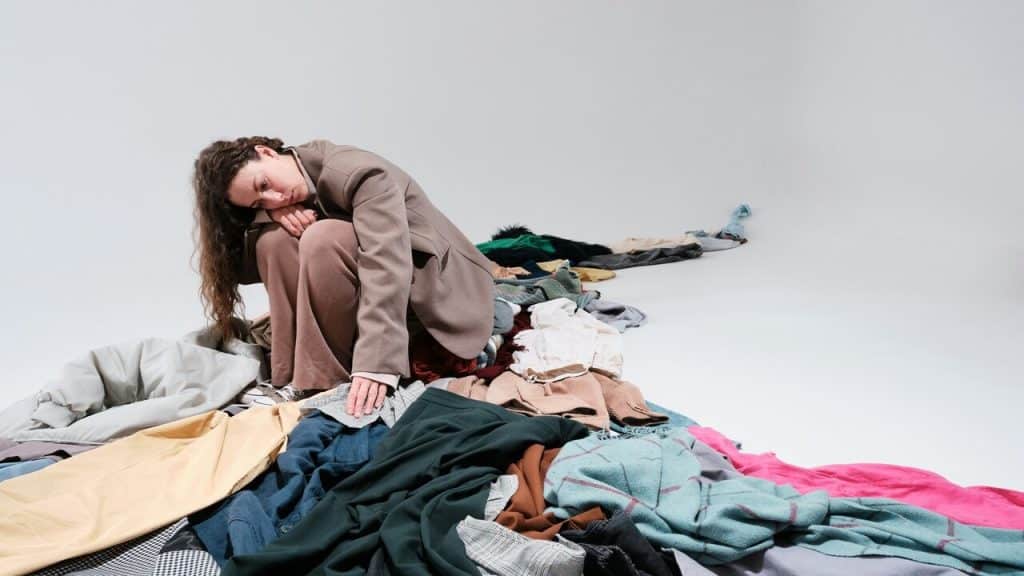 A woman looking sadly at a pile of clothes