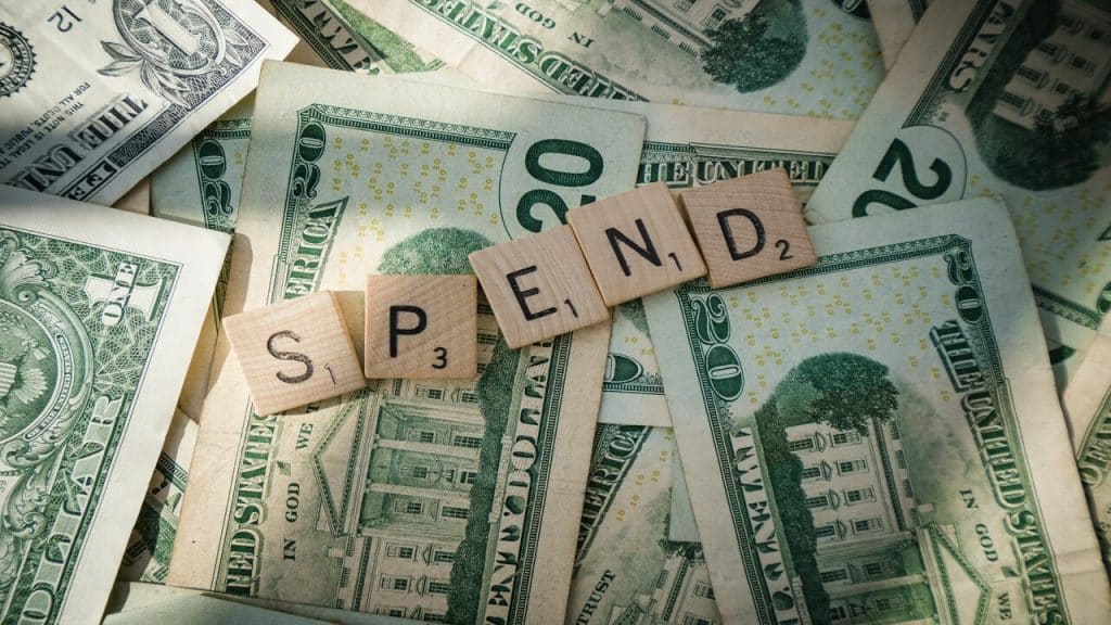 A pile of dollar bills with the word “Spend”