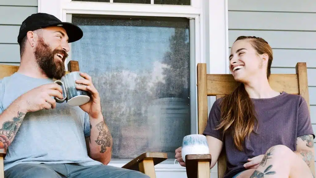 A man and a woman having tea while sitting on a porch.