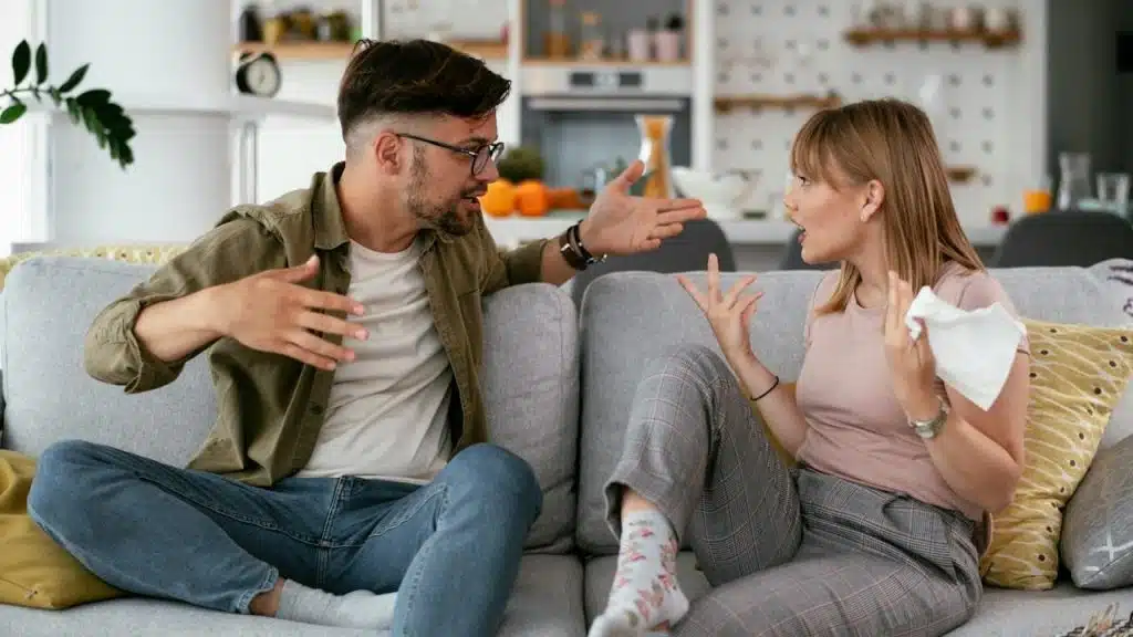 A man and a woman arguing while sitting on a couch.
