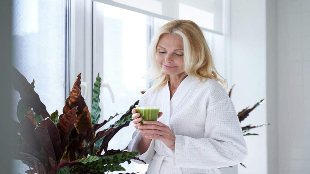 A beautiful mature woman drinking green juice