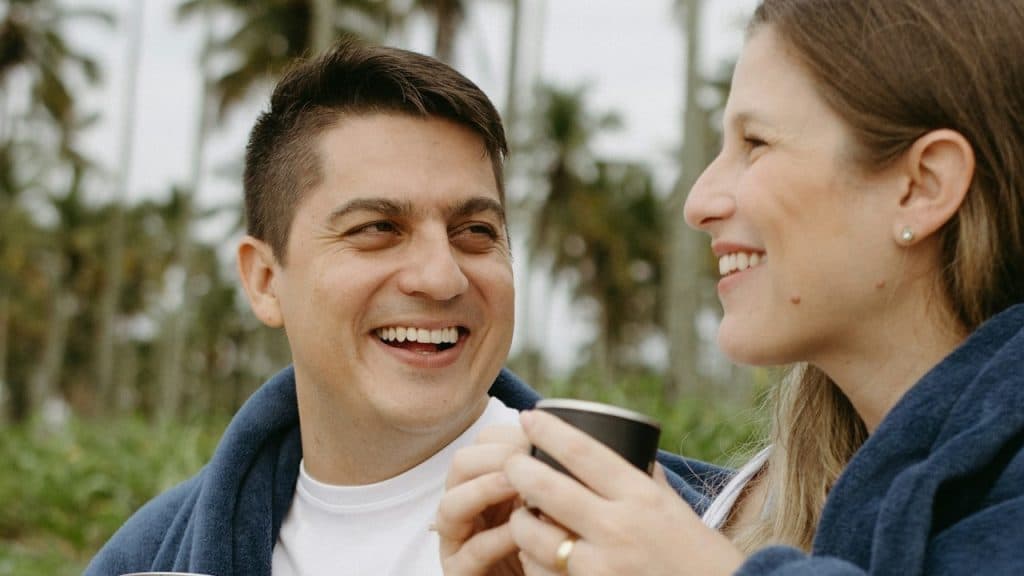 A man smiling at a woman holding a coffee cup.