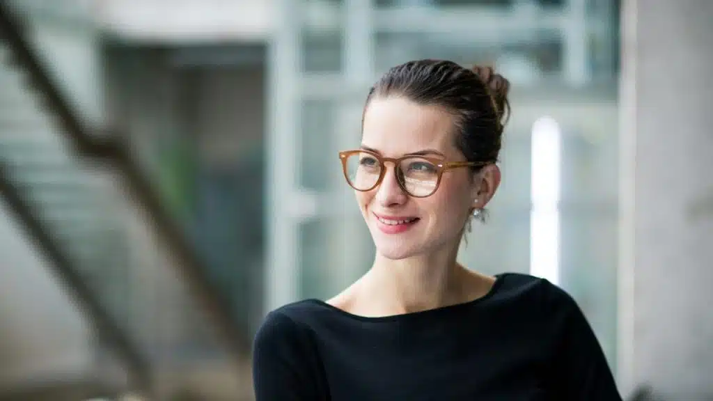 A woman is standing in a corridor outside an office.