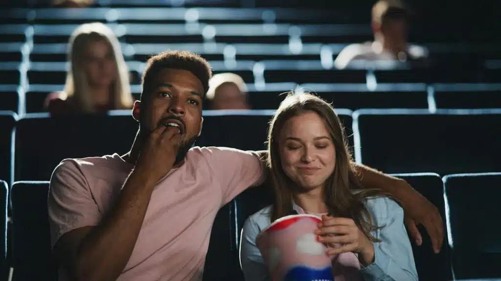 A couple at the movies and eating popcorn.