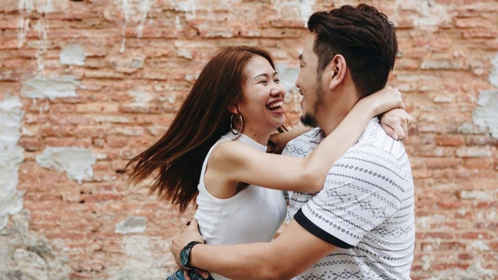 A woman smiling and hugging a man.