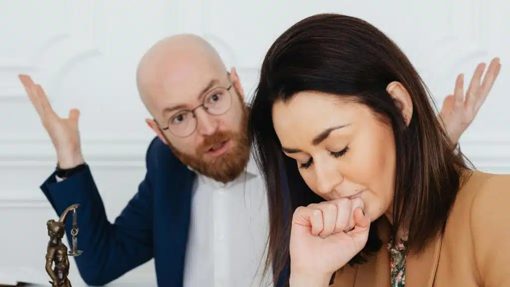 A man with glasses making fun of his partner who looks perturbed with closed eyes.
