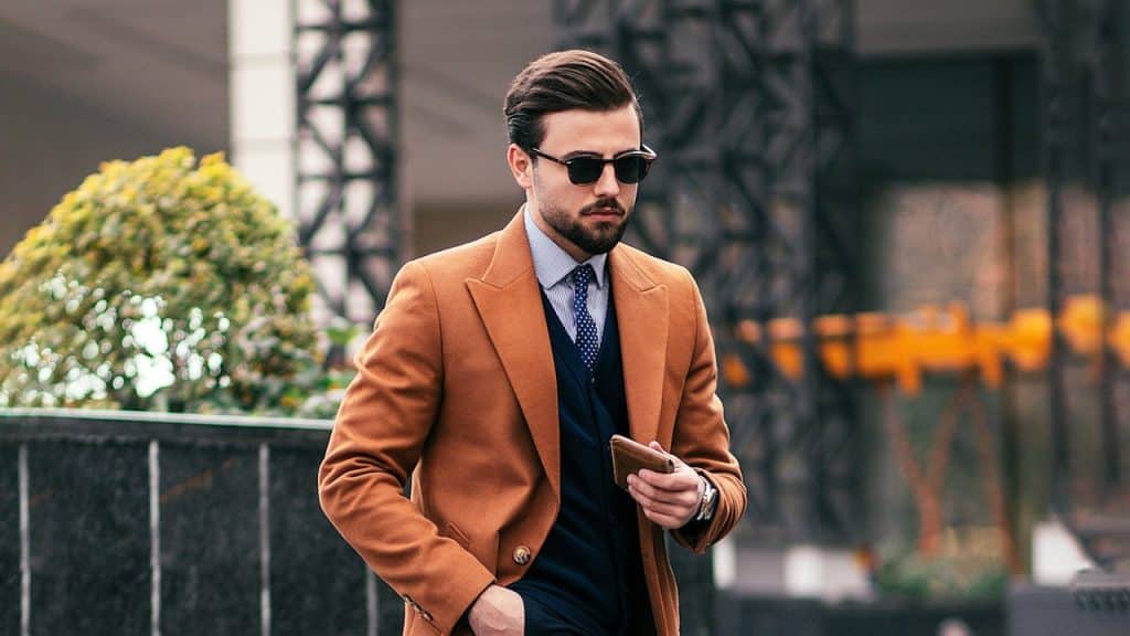 A man dressing decently is walking outdoors.