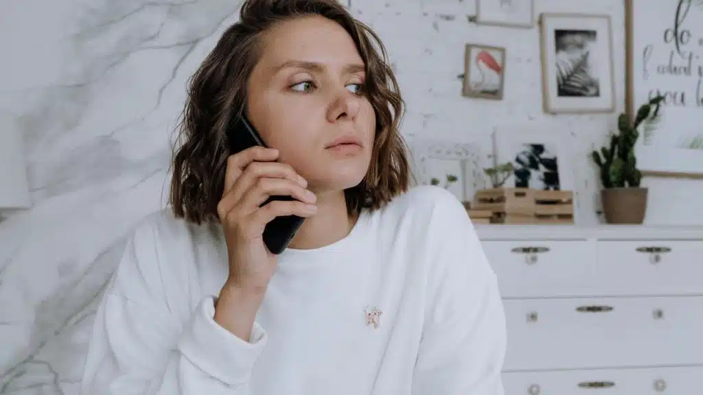 A woman holding a phone to her ear, looking concerned.