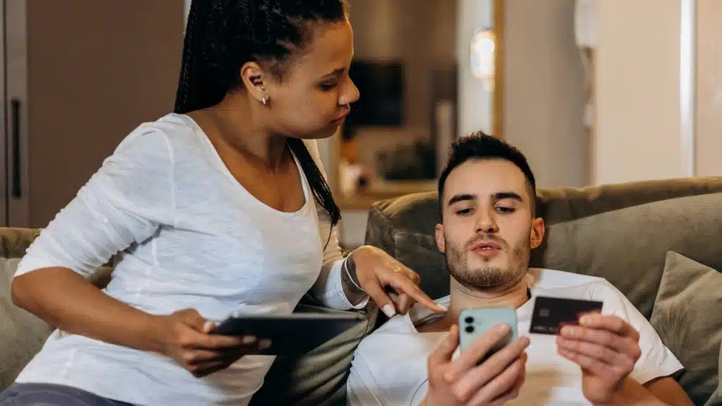 A woman points at a phone held by a man who is holding a card.