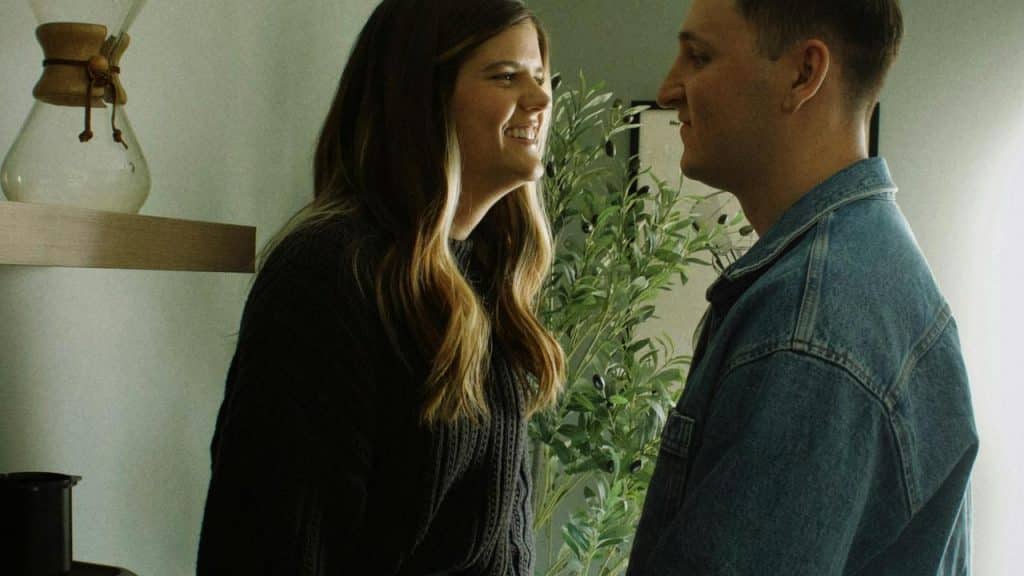 A couple standing face to face smiling at each other indoors