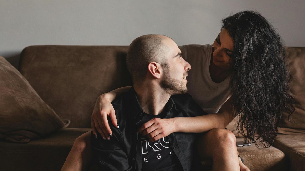 A couple sitting on a couch, gazing at each other.