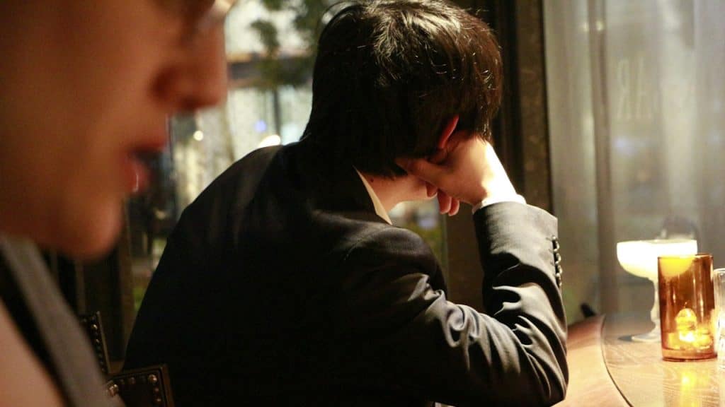 man-in-suit-resting-head-on-hand-at-bar