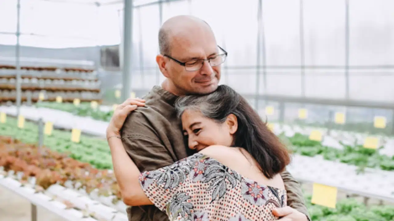 A mature couple hugging in a green house