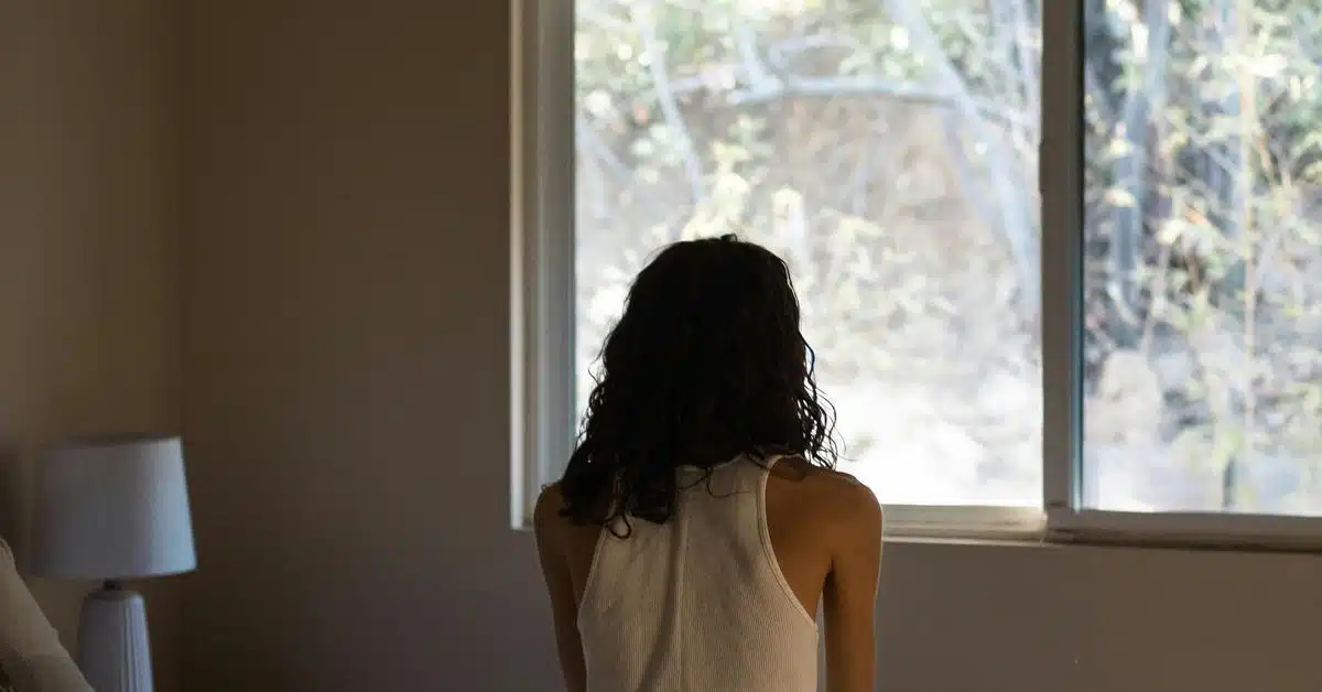 A person sitting with their back to the camera, looking out a window.