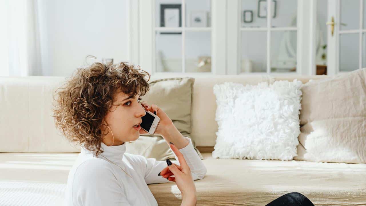 A woman sitting on the floor talking on her smartphone