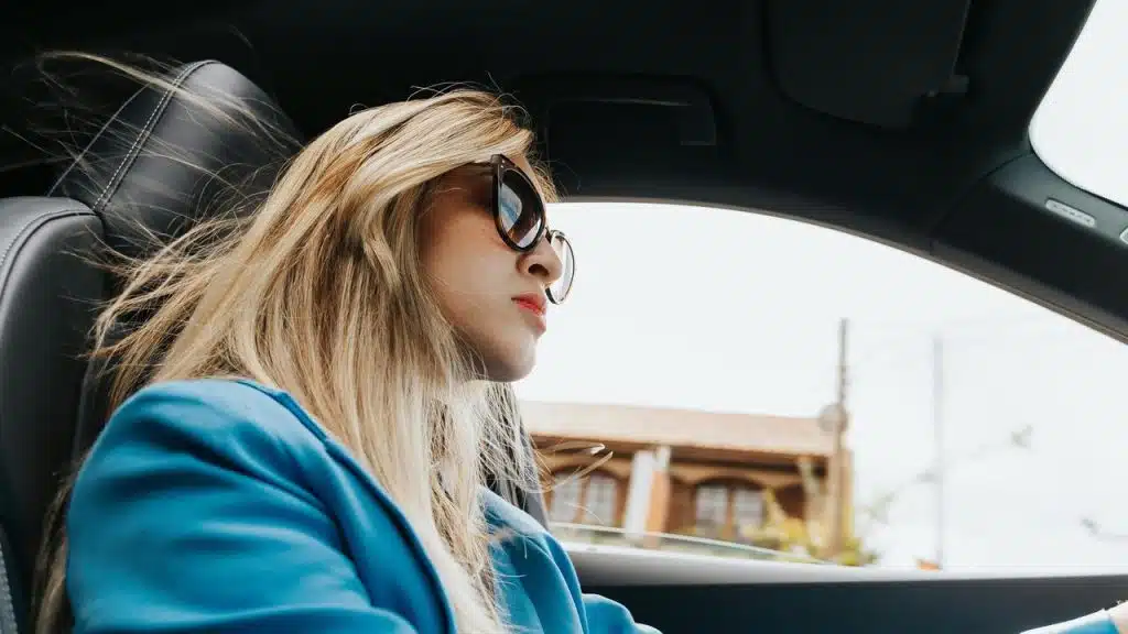 A woman wearing sunglasses driving a car.