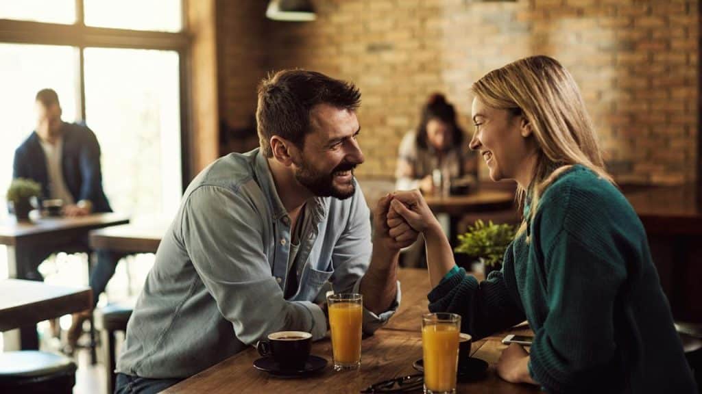 A man and a woman drinking juice while sitting in a restaurant together.