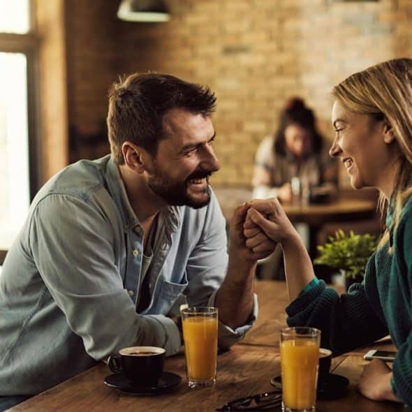 A man and a woman drinking juice while sitting in a restaurant together.