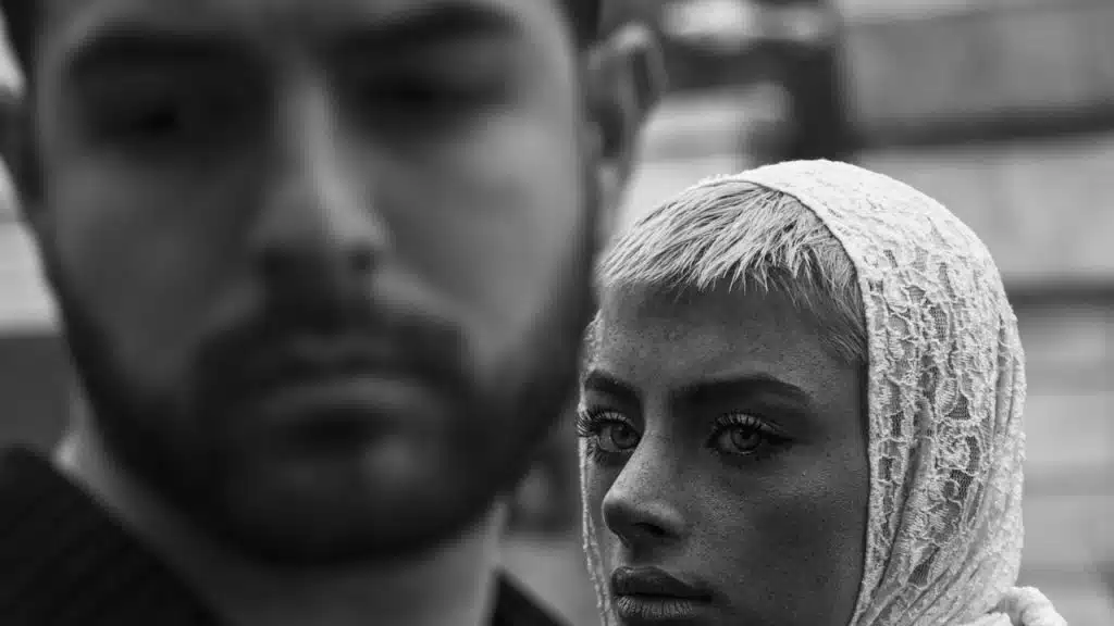 A woman in a veil gazes over a man standing next to her.