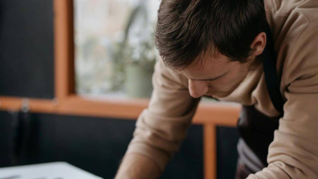 A man leaning over a table, focused on his work indoors.
