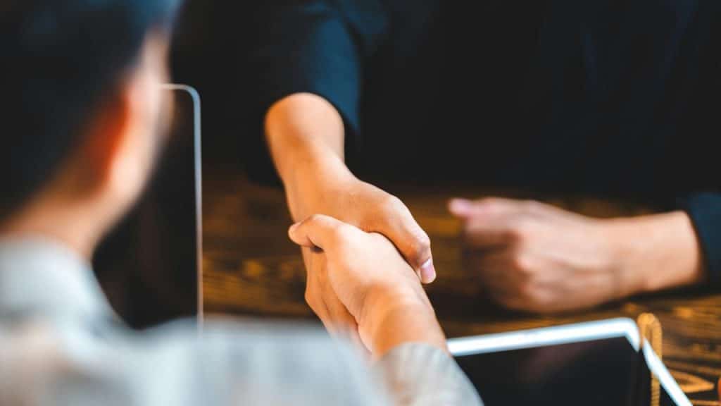 A close-up of two people shaking hands across a table.