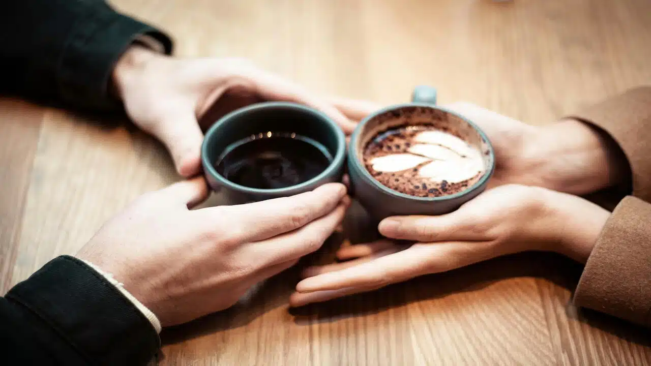 Two hands holding mugs of coffee