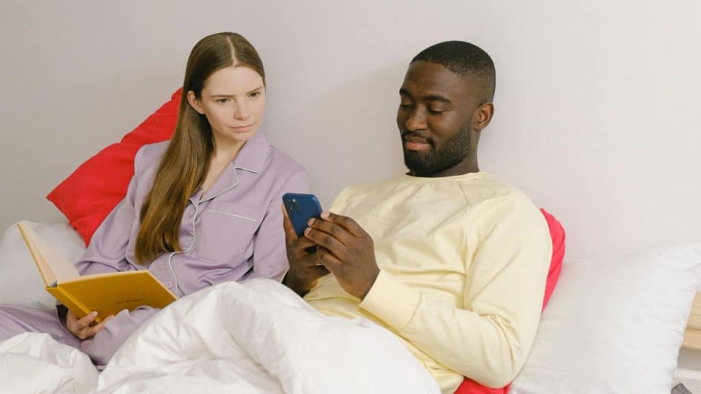A man looks at a smartphone while a woman beside him looks at the device.