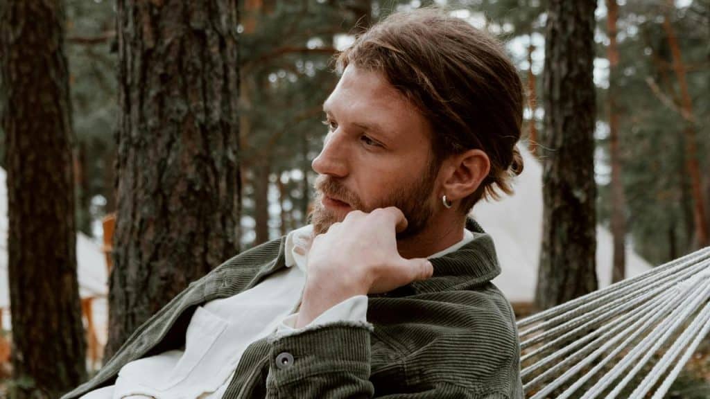 A man resting in a hammock in the woods.