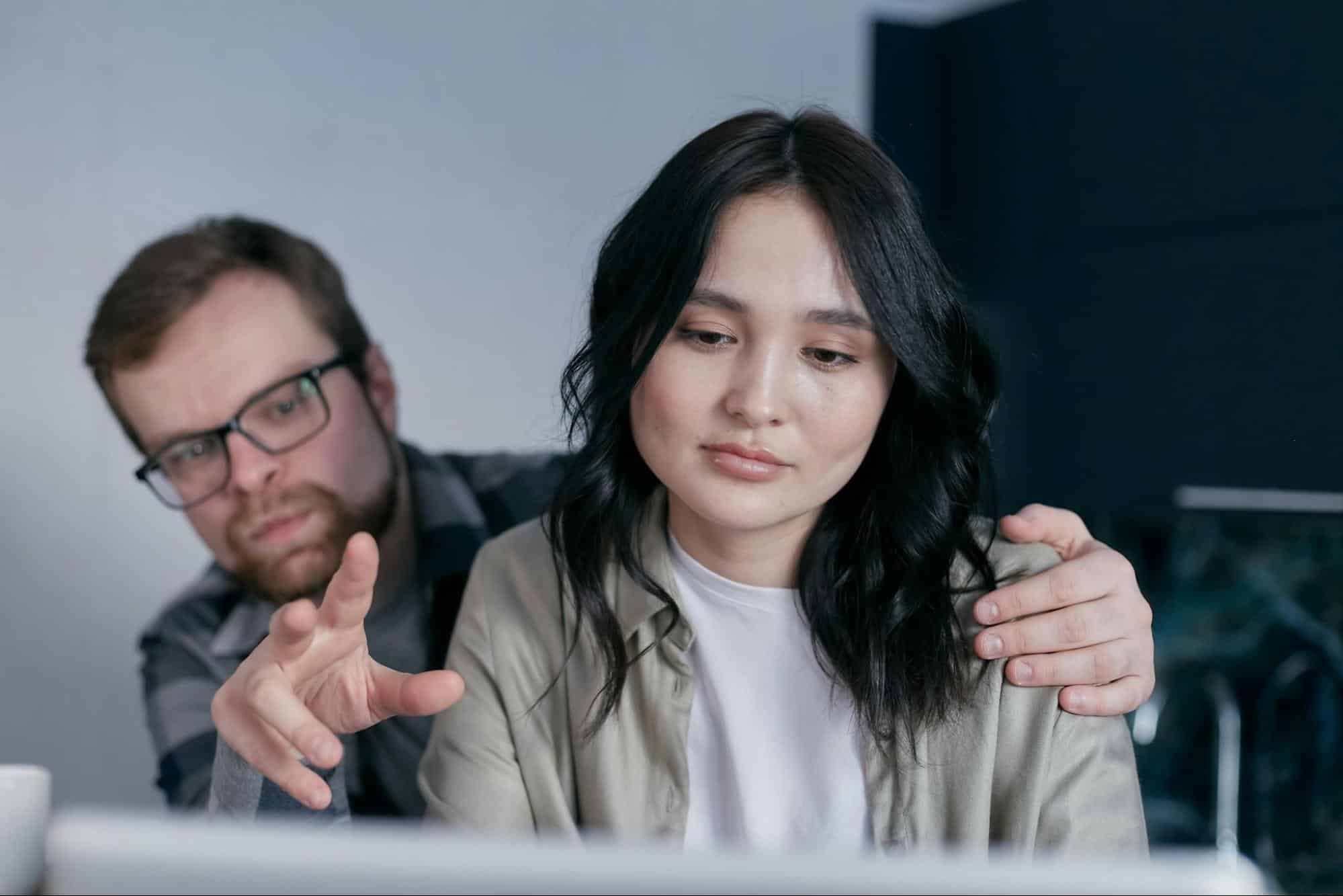 A man holding a woman’s shoulders from behind.
