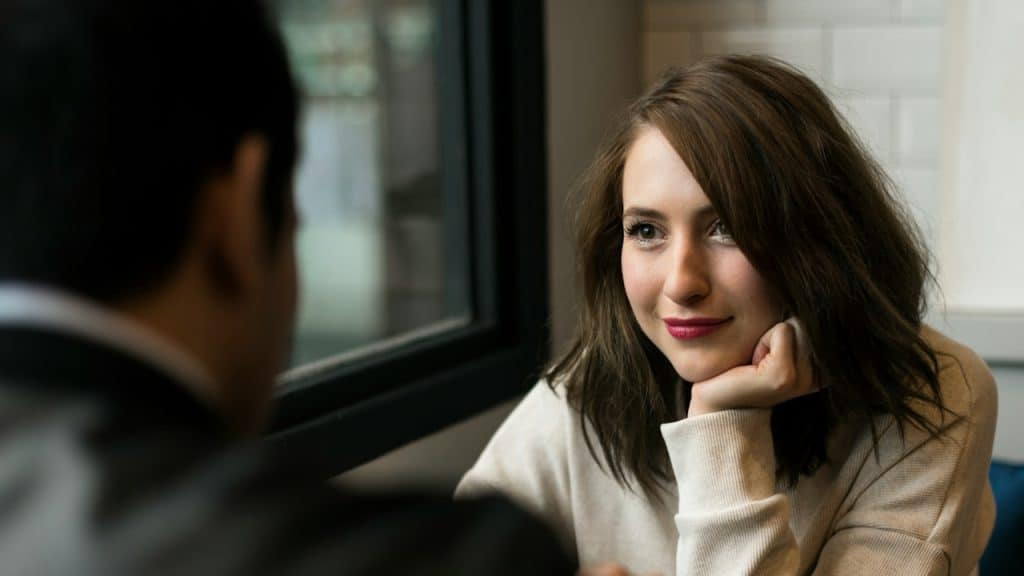 A man and a woman looking at each other while sitting together.