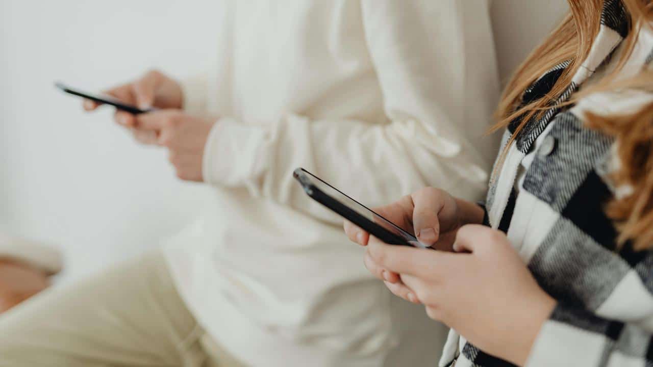 A close-up of two people using smartphones.
