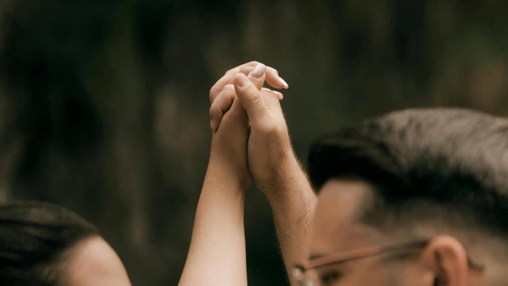 A pair of people clasping hands together in a gesture of connection.