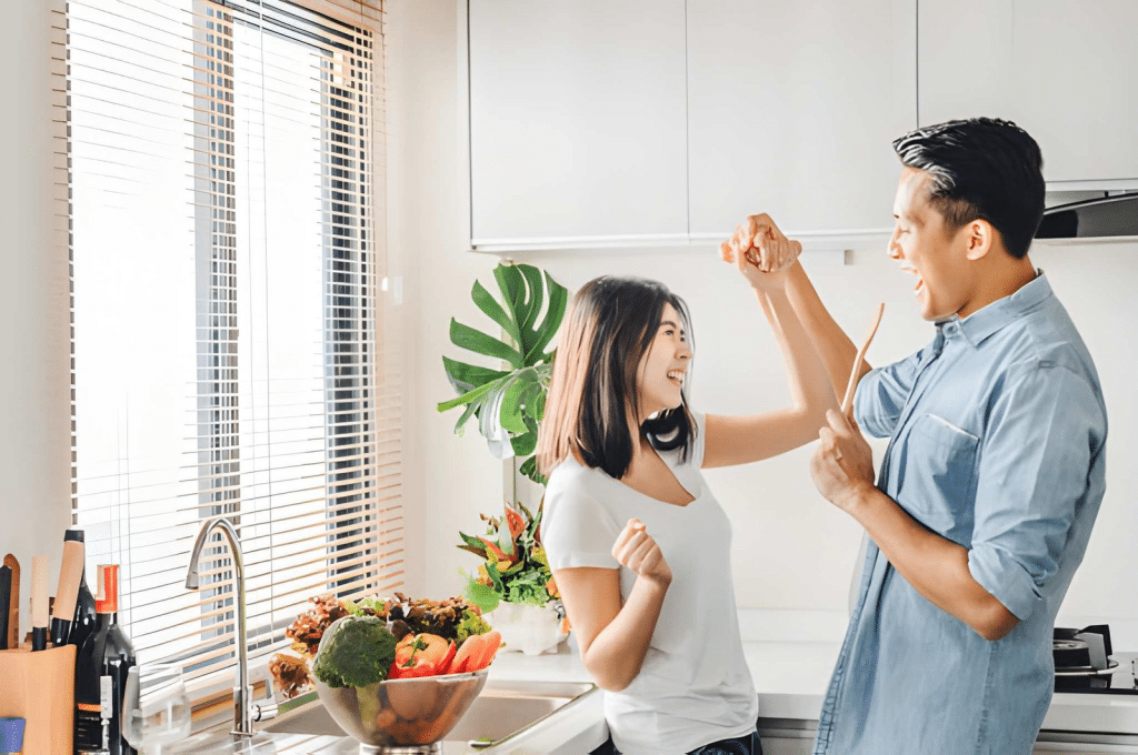 Young couple smiling and dancing together while in kitchen