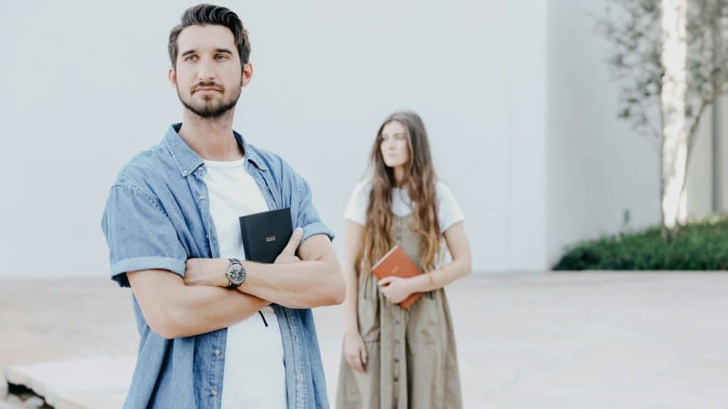 Man and woman standing near wall.