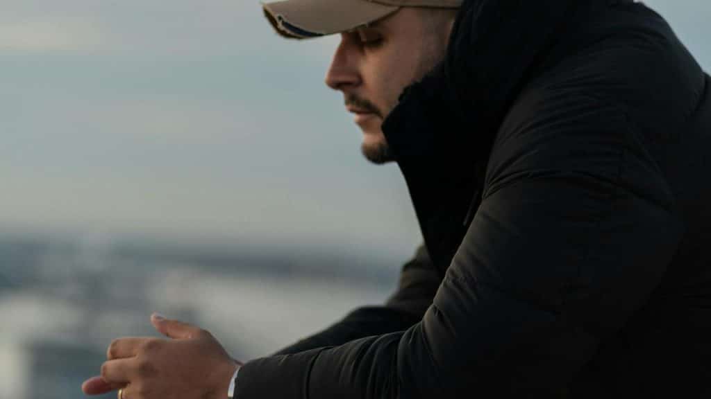 A person in a jacket looks out over the water in a quiet moment.