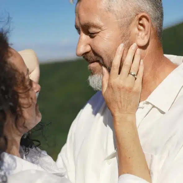 A couple smiling at each other while gently touching faces outdoors.