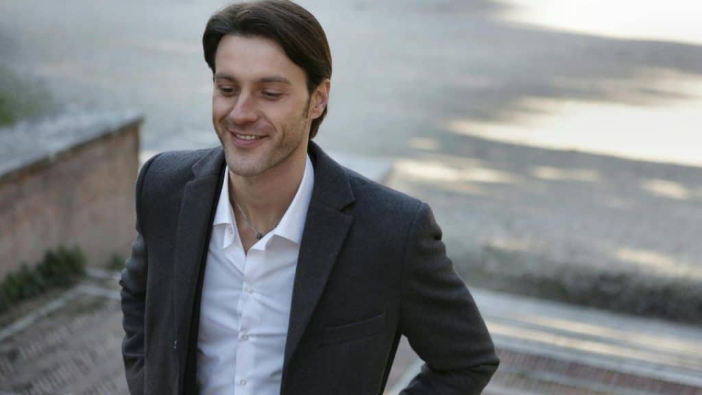 A smiling man in a suit outdoors.