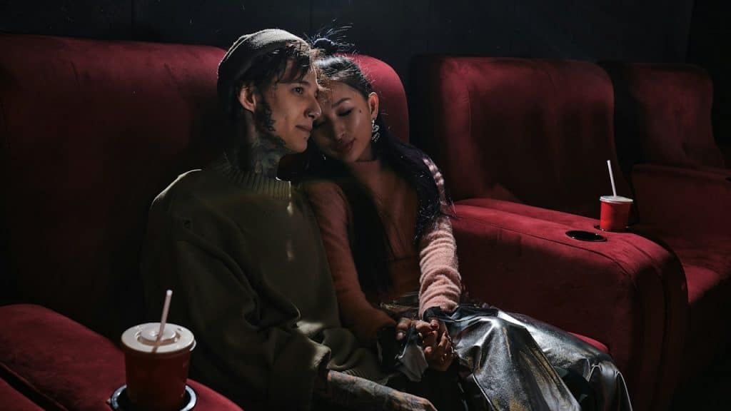 A man and a woman sitting on a red couch.