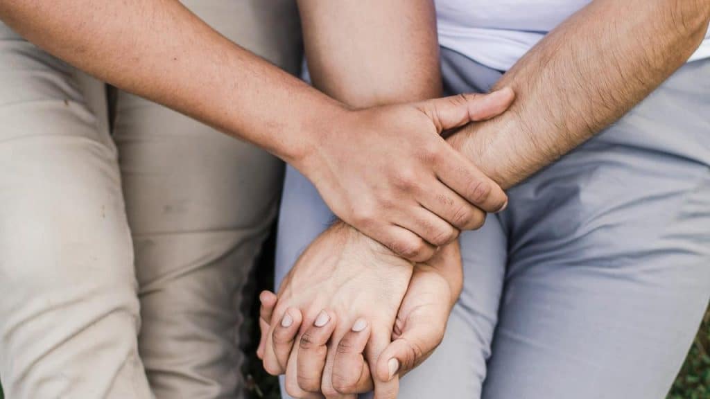 A close-up of two people holding each other’s hands.